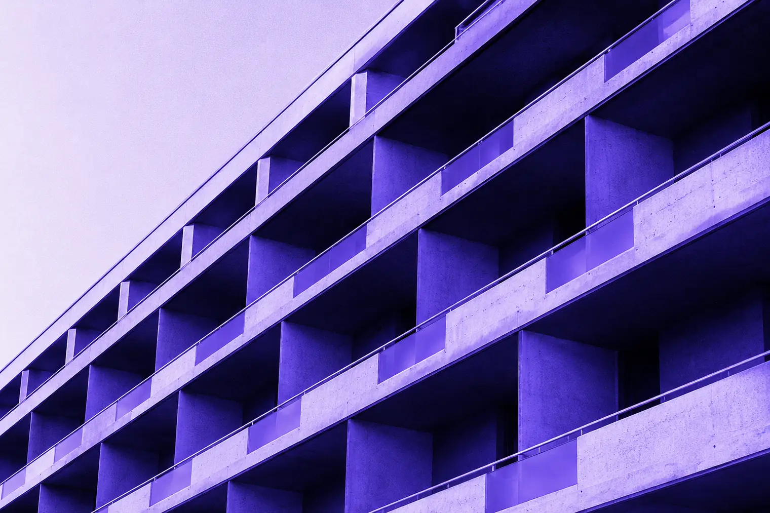 A concrete apartment façade of stacked balconies, seen from below.