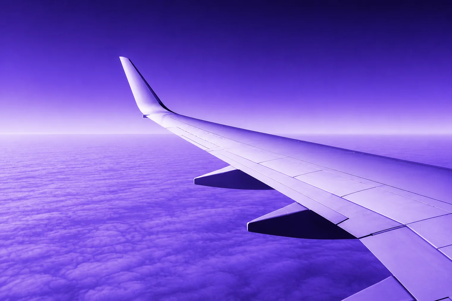 An aircraft wing above a cloud layer at altitude.